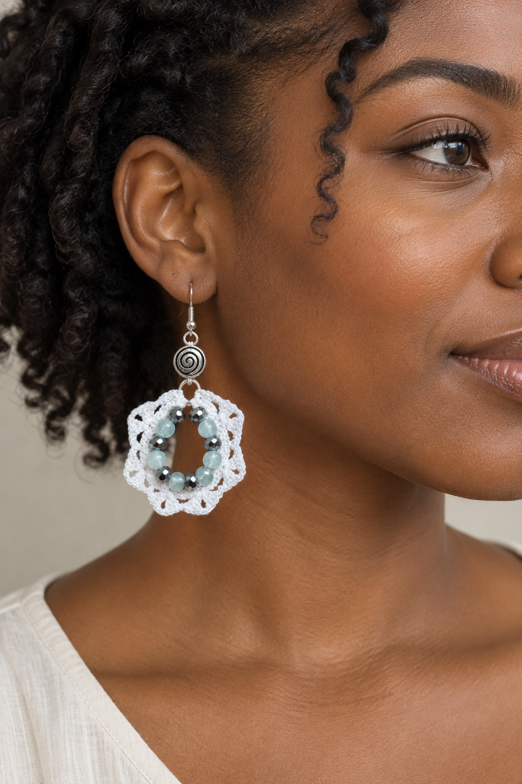 Visuel illustratif d’une boucle d’oreille en coton blanc et aigue-marine portée par une femme noire